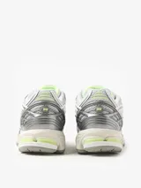 Championes urbanos New Balance modelo 1906R, con diseño técnico en tonos gris, blanco y detalles en verde lima. Presentan una estructura de malla transpirable con superposiciones sintéticas, logo N lateral y entresuela con tecnología de amortiguación.
