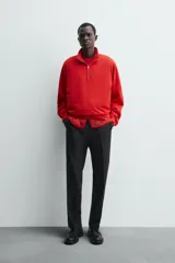 Sudadera de algodón ligero en color rojo, con cuello subido y cierre frontal de cremallera. Presenta mangas largas con puños acanalados y dobladillo inferior en rib.