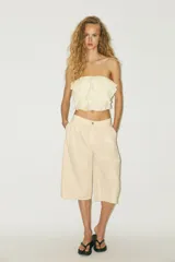 Top bandeau color crema con escote recto, hombros descubiertos y detalle de volantes en capas.