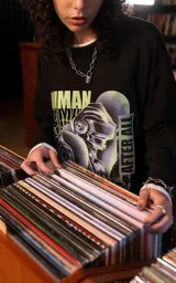 Remera de algodón premium con calce oversize, cuello redondo y mangas cortas. Presenta un estampado frontal gráfico con temática de Daft Punk en tonos verdes y violetas sobre fondo negro.