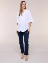 Blusa blanca de crepe crinkle con escote en V, media abotonadura frontal con botones nacarados, alforzas verticales en la pechera y mangas tres cuartos acampanadas con detalle de encaje horizontal.