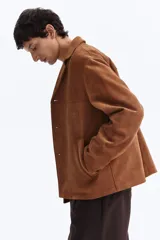 Campera marrón de tejido suave con acabado cepillado, solapas de muesca, cierre frontal de botones, bolsillos laterales insertados y canesú delantero y trasero.