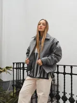 Campera gris con cierre frontal, cuello camisero y mangas largas con puños elásticos.