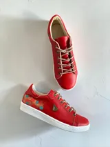 Championes de cuero rojo con detalles pintados a mano en el talón, suela blanca de goma y cordones beige.