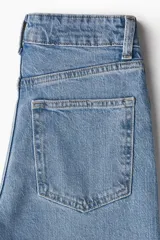 Pantalón de jean celeste de tiro alto, corte ancho y recto, con cinco bolsillos y cierre con botón.