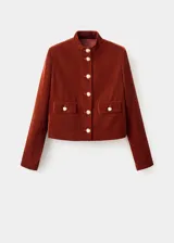 Chaqueta corta de terciopelo marrón con cuello mao, cierre frontal de botones dorados, mangas largas y dos bolsillos delanteros con solapa y botón.