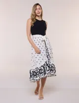 Vestido midi combinado de corte fluido. Presenta un torso ajustado acanalado sin mangas, con cuello redondo y sisas clásicas. Cuenta con cintura elastizada con lazo para anudar y falda evasé con estampado floral y geométrico, finalizando con un volante en el ruedo.