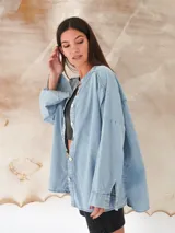 Camisa de denim liviano con lavado azul, cuello mao, manga larga y cierre frontal con botones de nácar. Presenta un corte holgado y oversize con ruedo redondeado.