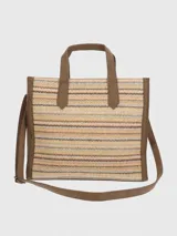 Cartera tipo tote de Hush Puppies con cuerpo de tejido trenzado en patrón de zigzag multicolor. Presenta detalles en cuero sintético marrón en las asas, bordes y base. Incluye un colgante decorativo con el logo de la marca y una placa metálica frontal con el nombre de la marca.