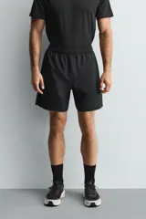 Pantalones deportivos cortos de tejido técnico ligero y elástico, con cintura elástica ajustable, bolsillos frontales y aberturas laterales en el bajo.