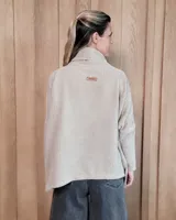 Polera de tejido suave con textura acanalada, cuello alto tipo tortuga, mangas largas y corte holgado con aberturas laterales en el ruedo.