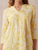 Blusa amarilla estampada con motivos florales en blanco, escote en V y mangas tres cuartos.