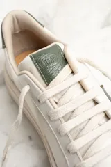 Zapatillas urbanas de cuero color blanco con detalles en verde.
