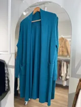 Saco largo color crema, de tejido de punto, con bolsillos laterales y corte recto.