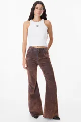 Pantalón de jean azul oscuro, corte acampanado (flare) de tiro alto, con costuras visibles en contraste y bordados tonales en la parte inferior de las piernas. El ruedo es deshilachado.