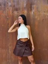 Minifalda tipo pareo confeccionada en cuero color chocolate, con diseño cruzado y cierre mediante tiritas laterales ajustables.