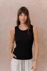 Musculosa acanalada de color negro, confeccionada en tejido fino, suave y liviano, con escote redondo y hombros anchos.