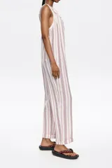 Mono largo de corte recto confeccionado en lino, con escote redondeado y tirantes con detalle de nudo ajustable. Presenta diseño de espalda nadadora y dobladillo en las piernas.