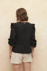 Blusa color verde claro con textura arrugada, escote en V, cierre frontal con botones, mangas 3/4 con puños elásticos y detalles de encaje y volados en el frente y los hombros.