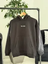 Canguro negro oversize de felpa, con capucha, bolsillo tipo canguro y diseño estampado en la espalda con gráficos estilo streetwear y texto en blanco.