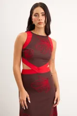 Vestido midi marrón con detalles en rojo, cuello redondo, diseño sin mangas, aberturas cut-out en la cintura y bordados artesanales de flores en contraste.
