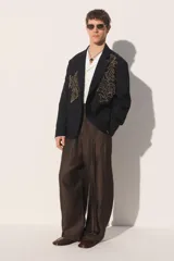 Blazer de corte relajado confeccionada en tejido con lana, color negro. Presenta cuello con solapas de muesca, cierre frontal de un botón y bolsillos de plastrón en la cadera. Destaca por su bordado en hilo dorado con motivos vegetales en la parte frontal.