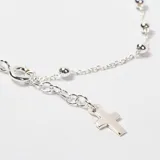 Pulsera de plata 925 tipo rosario, compuesta por una cadena de eslabones finos intercalados con pequeñas esferas metálicas y un dije de cruz colgante en el extremo.