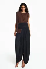 Mono largo bicolor con cuerpo drapeado en color marrón y parte inferior tipo pantalón bombacho en color negro. Presenta un diseño sin mangas con un hombro descubierto y una banda ancha ajustada en la cintura.