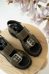Sandalias negras de cuero con diseño de plataforma dentada, tiras ajustables con hebillas metálicas y detalle de tachas plateadas en el lateral de la suela.