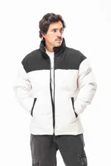 Campera puffer con diseño bicolor, presentando la parte superior en color negro y la parte inferior en color blanco. Cuenta con cuello alto, cierre frontal completo y bolsillos laterales con detalles en negro.