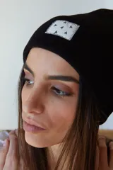 Gorro de lana color lila con etiqueta cuadrada blanca con diseño de triángulos negros.
