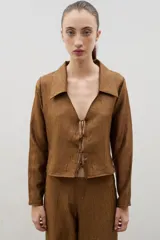 Camisa de manga larga color marrón con textura arrugada, cuello clásico y cierre frontal mediante lazos para anudar.
