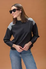 Sweater de punto color negro con cuello redondo y mangas largas, destacando por sus paneles de cuero sintético gris en los hombros.