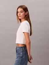 Remera cropped blanca de manga corta y cuello redondo, con logo gráfico de Calvin Klein impreso en el pecho.