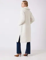 Tapado largo color blanco de tejido bouclé, marca Bcbg Maxazria. Cuenta con cuello de solapa amplia, cierre frontal con botones a presión internos, bolsillos funcionales y tajos laterales en el bajo. Forro interno a tono.