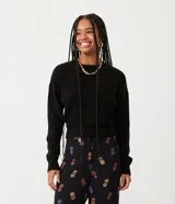 Suéter negro de punto con textura acanalada, cuello redondo y mangas largas.