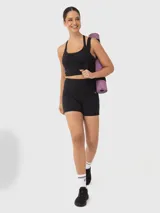 Top deportivo tipo crop top color negro con sujetador interior integrado, escote redondo y diseño de tiras finas cruzadas en la espalda.