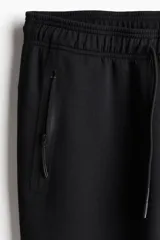Jogger deportivo negro de corte ajustado, confeccionado en tejido funcional DryMove™ que absorbe el sudor. Presenta cintura elástica con cordón de ajuste, bolsillos laterales con cierre sellado y piernas ajustadas.