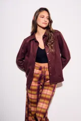 Camisa color marrón de gamuza sintética, de corte recto, con cuello clásico, cierre frontal con botones y mangas largas.