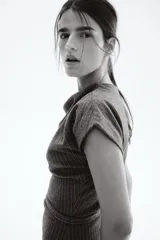 Vestido midi gris oscuro con finas rayas verticales blancas, escote drapeado tipo barco y mangas cortas caídas. Se ajusta a la cintura con un cinturón fino del mismo tejido y hebilla cuadrada.