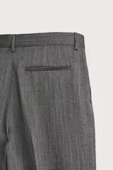 Pantalón de traje gris de corte relaxed fit, confeccionado en pura lana, con bolsillos laterales, bolsillos traseros de doble vivo y raya marcada en las piernas.