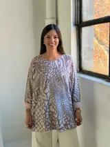 Sweater de punto con diseño holgado y estampado animal print que combina motivos de cebra y serpiente en tonos neutros. Presenta cuello redondo y mangas largas con puños vueltos.