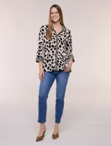 Camisa holgada de rayón con estampado animal print de manchas negras sobre fondo beige, cuello camisero y abotonadura frontal con detalles de estampa estilo cebra. Cuenta con mangas tres cuartos y ruedo curvo.