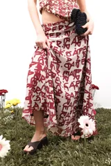 Falda larga de gasa con estampado tipográfico en color bordó sobre fondo beige. Presenta una silueta fluida y cierre lateral oculto.