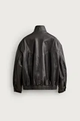 Cazadora relaxed fit de tejido efecto piel en color marrón oscuro con acabado lavado. Cuenta con cuello subido, bolsillos con solapa en la parte frontal, bajo y puños elásticos, y cierre frontal con cremallera y solapa con botones a presión.