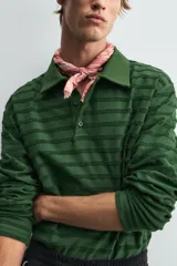 Polo de manga larga con cuello solapa y cierre frontal de botones. Presenta un tejido jacquard texturizado con rayas horizontales en tonos de verde.