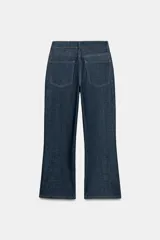 Jeans de tiro medio con corte cropped flare, confeccionados en denim azul oscuro. Presentan diseño de cinco bolsillos, trabillas en la cintura, raya planchada en el delantero y bajo con acabado evasé. Cierre frontal con cremallera y botón metálico.
