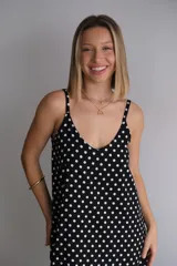 Vestido largo de crepe con estampado de lunares negros sobre fondo blanco. Presenta un diseño de corte holgado con breteles finos y escote redondeado.