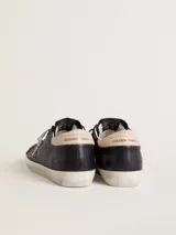 Zapatilla Golden Goose modelo Super-Star, confeccionada en cuero vacuno negro con efecto desgastado. Presenta la clásica estrella lateral de pelo con patrón animal print tipo cebra, contrafuerte en cuero nude y cordones con hilo plateado. Suela de goma con acabado envejecido y detalles con inscripciones doradas.