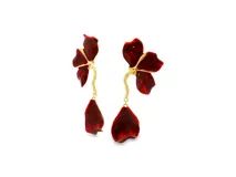 Pendientes largos con diseño floral escultural en metal dorado y esmalte rojo intenso, con pétalo colgante de un tallo dorado texturizado.